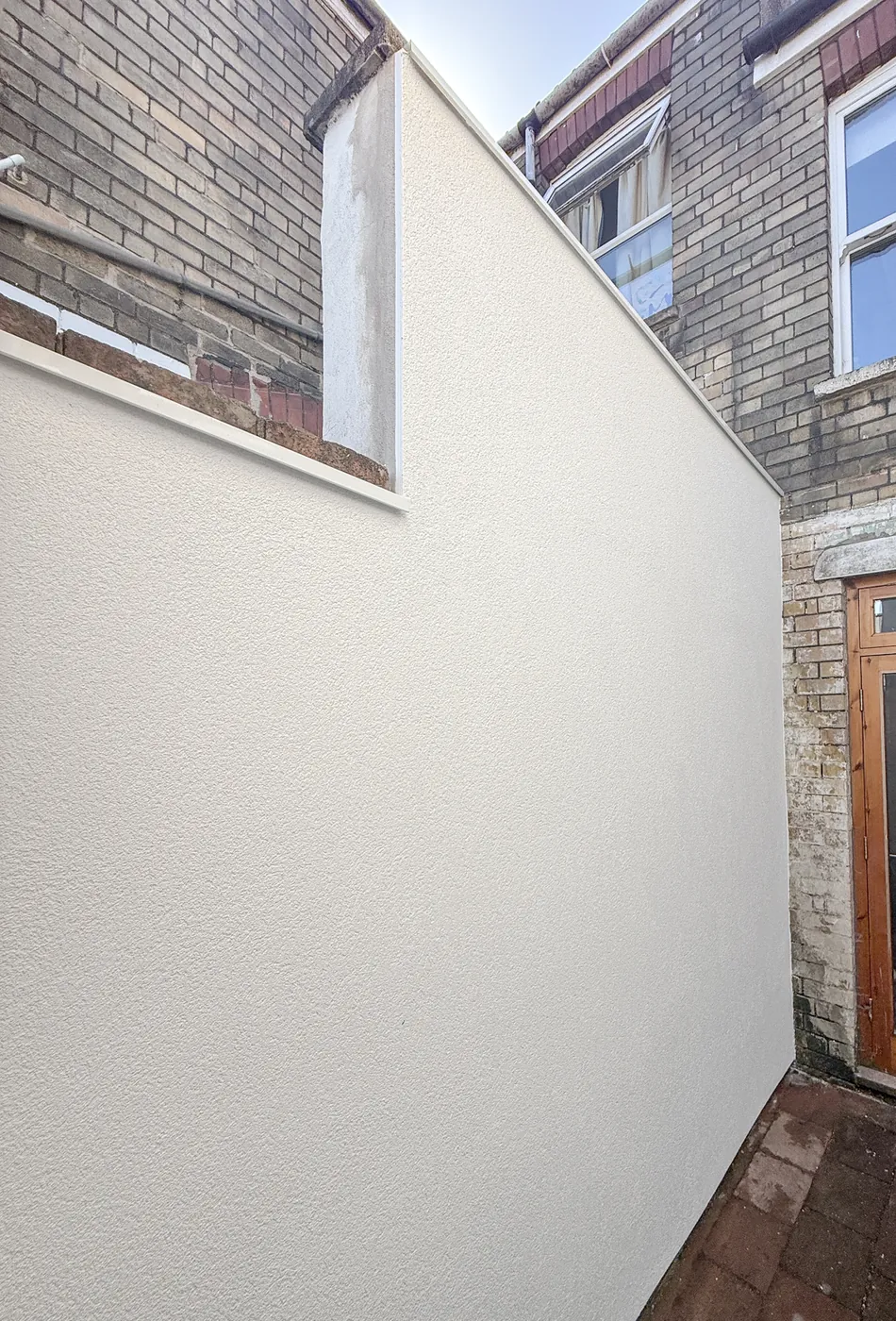 Completed premium silicone thin-coat render with custom aluminium capping on a party wall in Bedminster, Bristol BS3